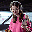 Žena s nasazenými sluchátky poslouchá hudbu na smartphonu Xperia 5 IV