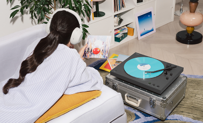 En person med hörlurar som håller i ett vinylfodral med PS-LX3BT som spelar