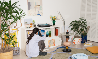 En person väljer en vinylskiva bredvid en PS-LX3BT i ett vardagsrum