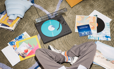 PS-LX3BT reproduciendo un vinilo turquesa con varios discos repartidos por el suelo