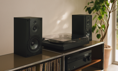 Plattenspieler PS-LX5BT mit geschlossener Staubabdeckung zwischen zwei Lautsprechern