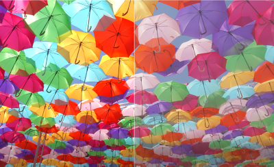 Image comparative de parapluies colorés dans un ciel clair. Le côté gauche montre des couleurs riches avec la technologie XR Triluminos Pro, tandis que le côté droit présente les couleurs sans cette technologie, plus ternes.