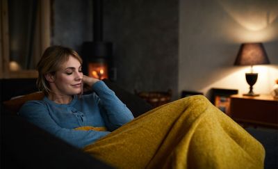 תמונה של אישה שוכבת על ספה עם שמיכה ומאזינה למוזיקה