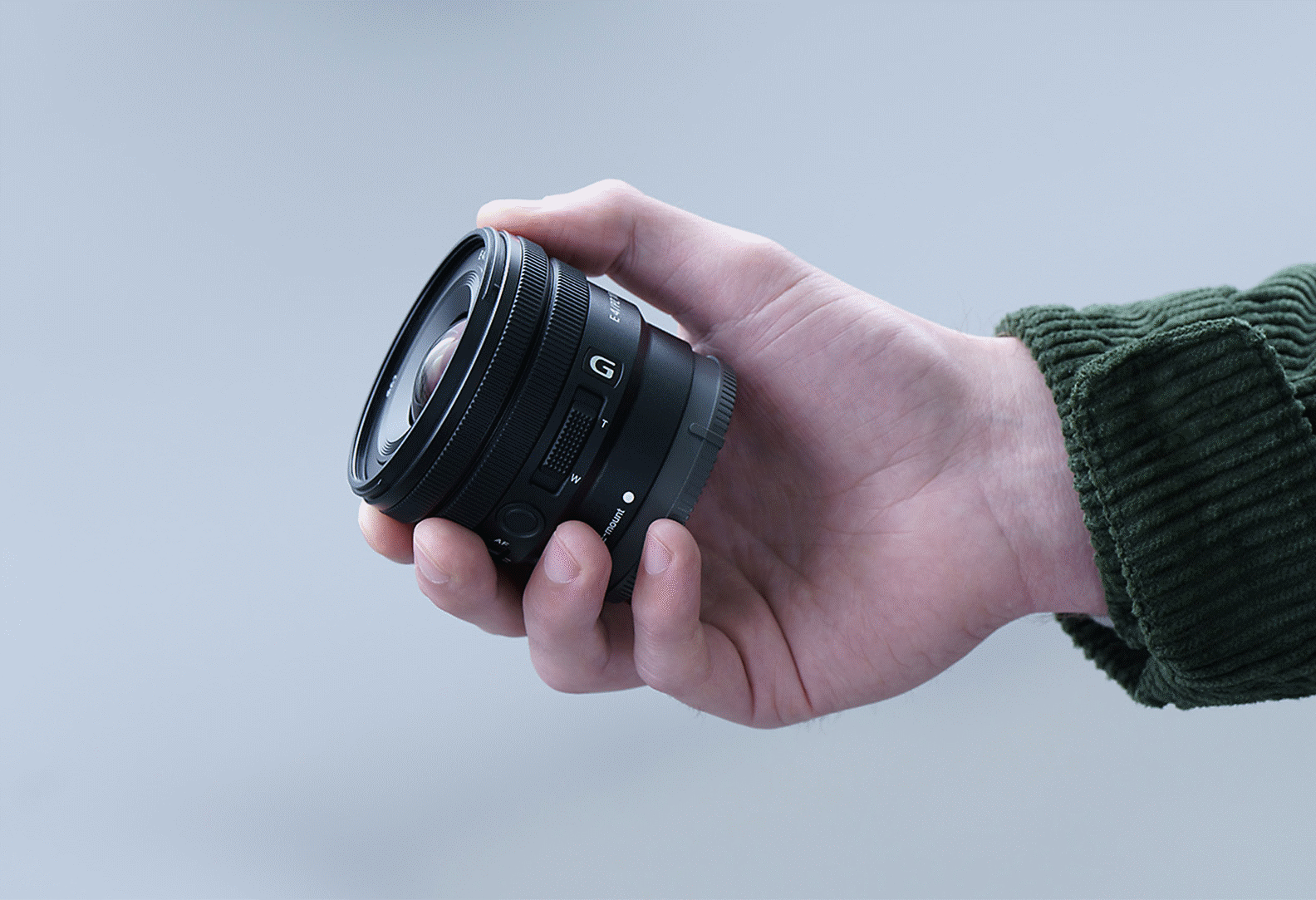 Изображение руки человека с объективом E PZ F4 G (10–20 мм), на котором объектив помещается в руке