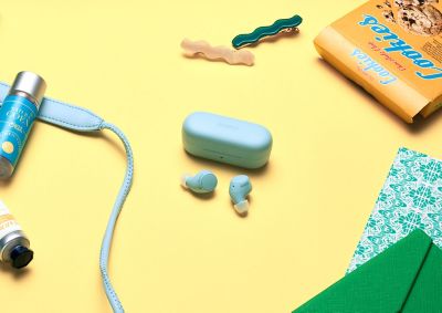 WF-C510 earbuds sat on a table with respective blue earbuds case, with other personal accessories on the table
