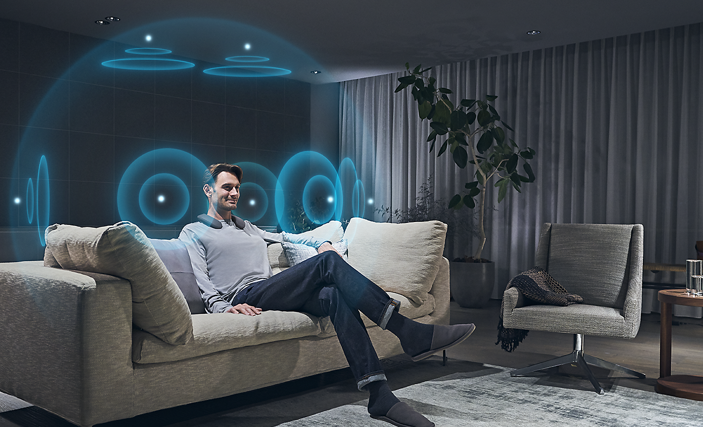 Mann in einem Wohnzimmer mit Darstellung von blauen Klangwellen, die für 360 Spatial Sound stehen