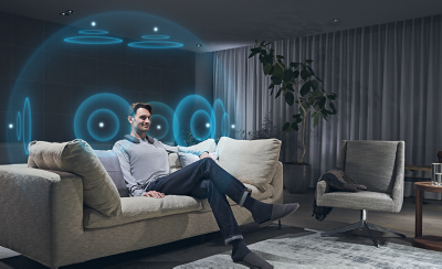 תמונה של איש בסלון עם איור של גלי קול כחולים המייצגים צליל מרחבי 360
