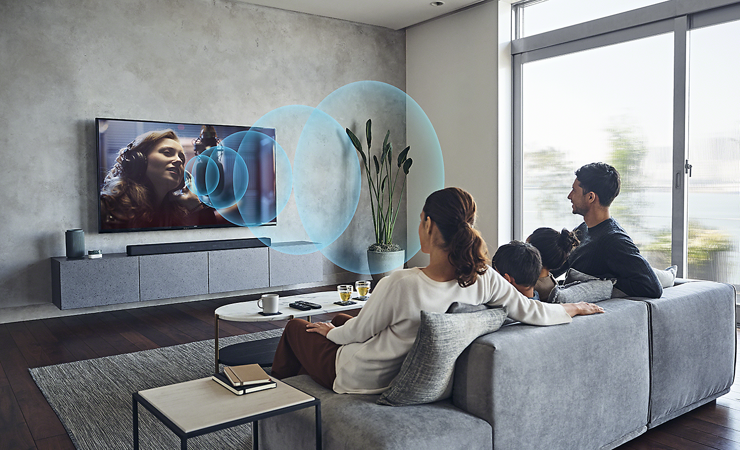 Image of family in living room watching BRAVIA TV with illustrated blue sound waves representing Acoustic Centre Sync