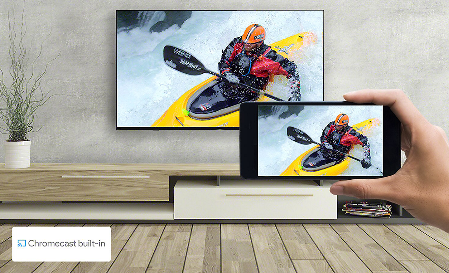 Una mano sostiene un smartphone frente a una TV montada en la pared. En ambas pantallas se ve la misma imagen de piragüismo. Un logotipo de Chromecast built-in aparece en la parte inferior izquierda.