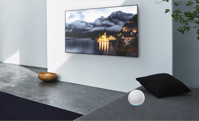Living-room scene showing a TV on the wall with an Alexa device to the side