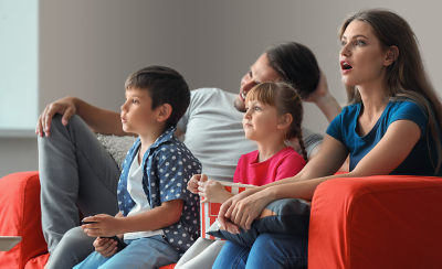 A family of four on a sofa, transfixed by what they're watching on TV