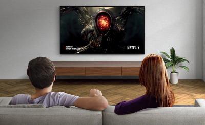 תמונה של זוג בסלון צופה ב-Netflix בטלוויזיית BRAVIA המותקנת על הקיר
