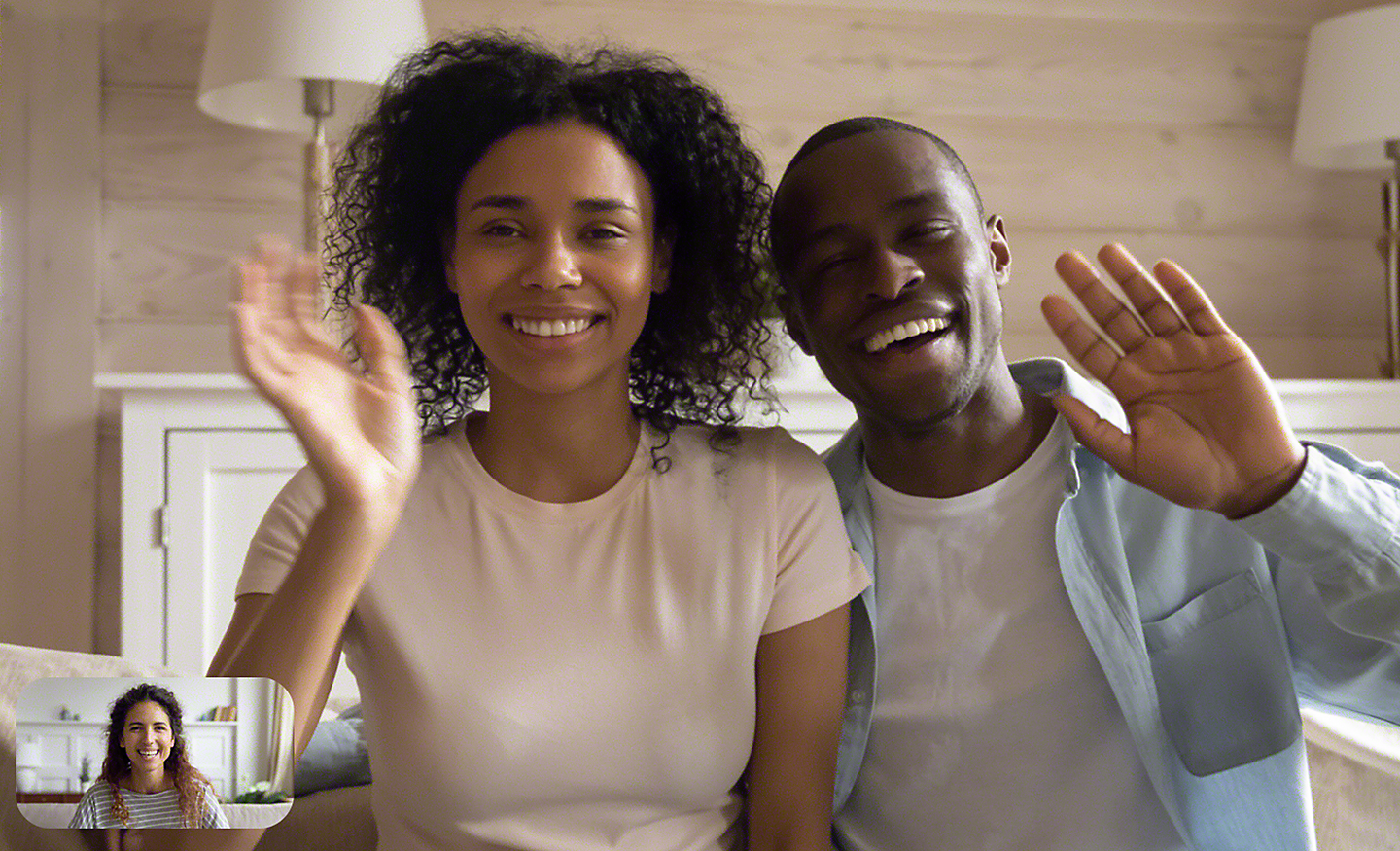 一對情侶在客廳中於視訊聊天時對朋友揮手的影像