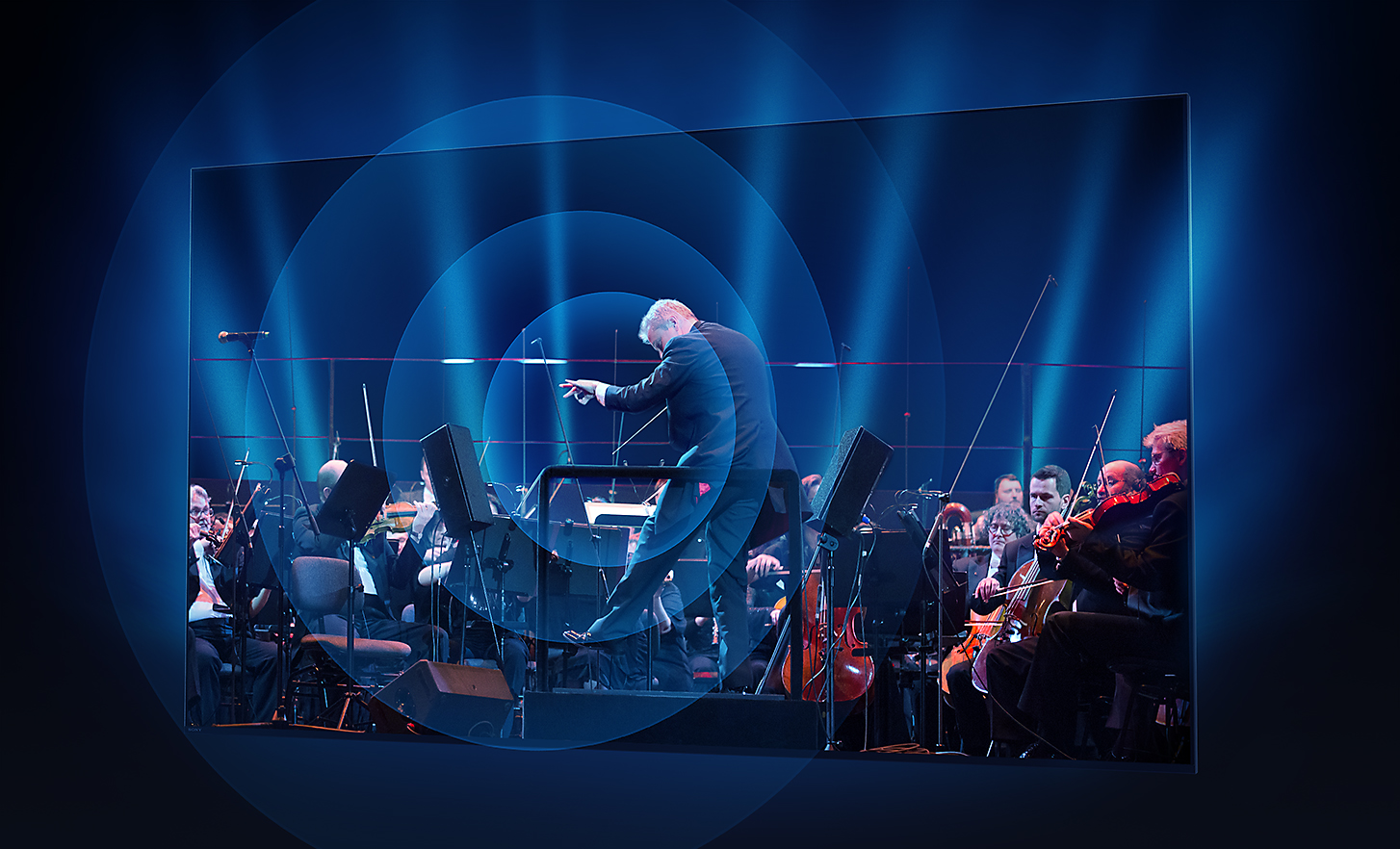 BRAVIA televízió képernyője, amelyen egy karmester és a zenekara látható; hanghullámok sugároznak ki koncentrikus körökben a képernyő középpontjából
