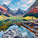 Image of a lake surrounded by mountains and trees with incredibly rich, vivid colours