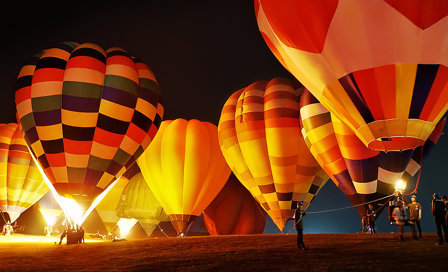 Slika raznobojnih balona na vrući zrak koji polijeću po noći