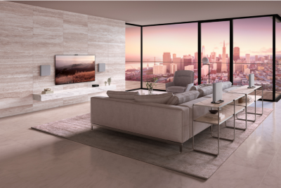 Light brown sofa, table and chair in a living room with wall-mounted TV and soundbar on a plinth, and glass wall to the right overlooking a cityscape