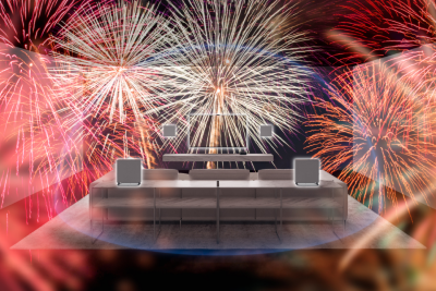 Grey sofa in a living room with wall-mounted TV and surround speakers to each side, soundbar on a plinth, and fireworks filling the room