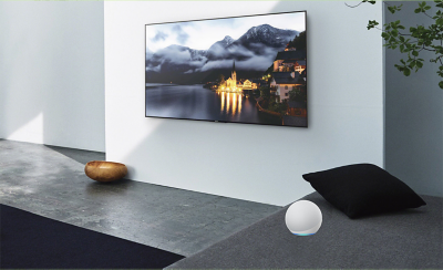 Angled view of wall-mounted TV above marble plinth with screenshot of town on lake with mountains behind