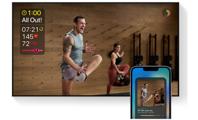 Ảnh chụp màn hình nhiều người đang tập luyện trong phòng tập thể dục với dữ liệu ở bên trái màn hình và nửa trên của chiếc điện thoại thông minh ở tiền cảnh hiển thị ứng dụng thể dục trên màn hình