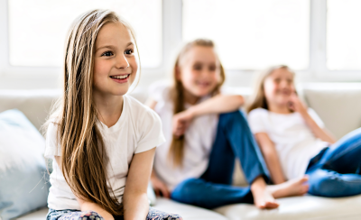 Image of three children sitting on a sofa watching TV