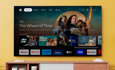 Wall-mounted TV above a wooden cabinet with books left and right and screenshot of The Wheel of Time with a variety of apps highlighted below