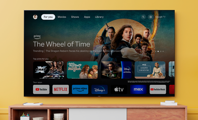 Wall-mounted TV above a wooden cabinet with screenshot of The Wheel of Time with a variety of apps highlighted below