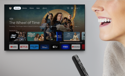 Wall-mounted TV with screenshot of The Wheel of Time and a variety of content below with a person's face and remote commander to the right side