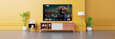 Wall-mounted TV above wooden cabinet with screenshot of Google TV apps