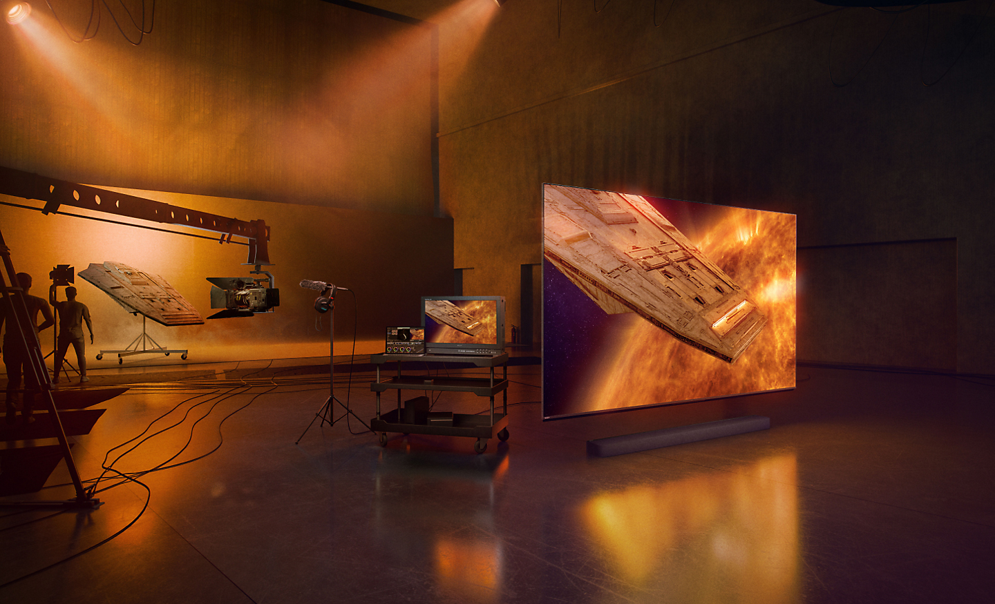 Studioszene mit der Silhouette von Technikern und Produktionsbearbeitungsausrüstung links und Schrägansicht eines Fernsehers und einer Soundbar rechts; auf dem Bildschirm ist ein Raumschiff in einer nebligen roten und blauen Umgebung zu sehen