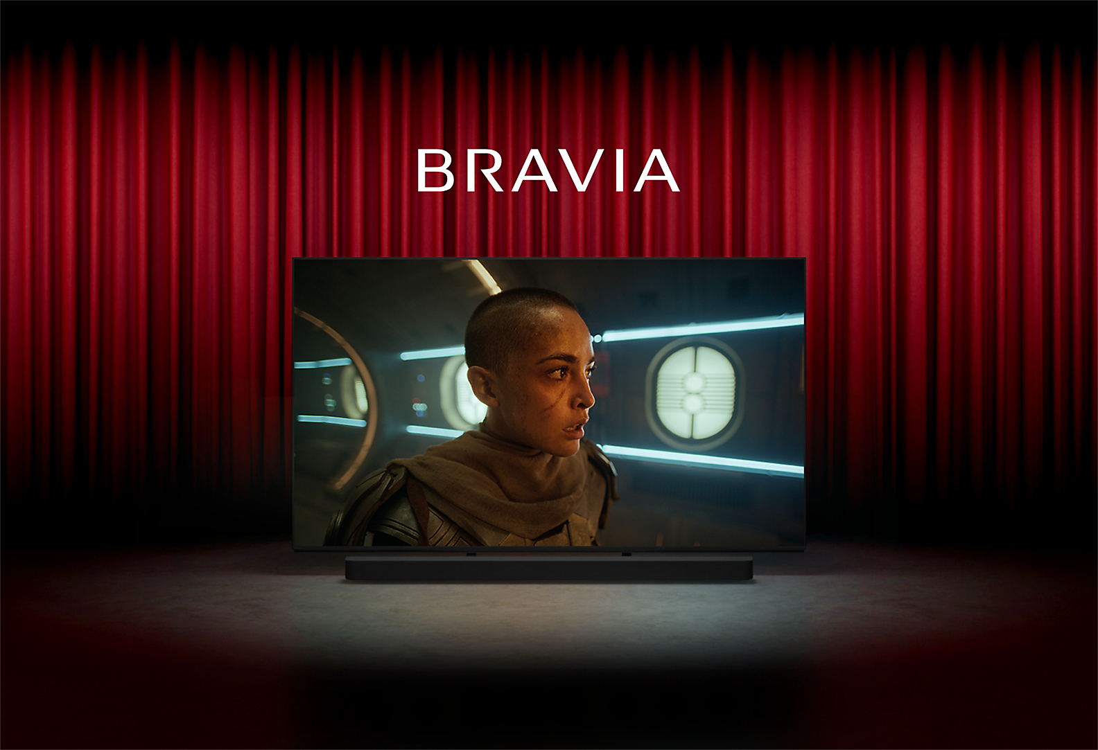 Bild eines Kinos mit roten Vorhängen und Sony TV mitten auf der Bühne; auf dem Bildschirm ist eine Person in einem Science-Fiction-Film zu sehen, das Wort BRAVIA darüber und eine Soundbar von Sony darunter