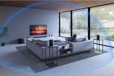 Grey sofa, table and chair in a living room with wall-mounted TV and soundbar on a plinth, and glass patio doors to the right overlooking a garden