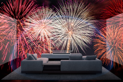 Grey sofa in a living room with wall-mounted TV and soundbar on a plinth, and fireworks filling the room