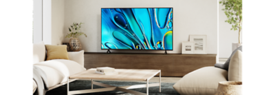 Living room scene with coffee table centre and TV on a large wooden cabinet with screenshot of blue water droplets