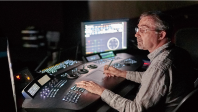 Person sitting at editing desk in studio with console and monitor