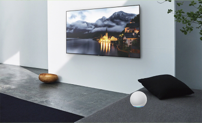 Image d'un salon avec un téléviseur sur le mur et un appareil Alexa sur le côté.
