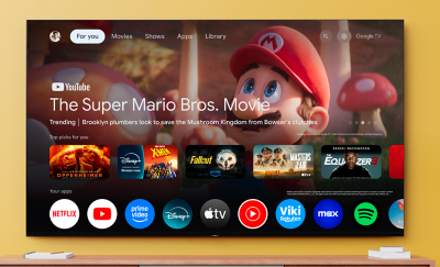 Large TV mounted on wall displaying Google TV interface, featuring The Super Mario Bros. Movie. Streaming apps shown below.
