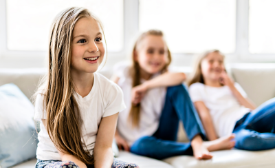 Image of three children sitting on a sofa watching TV.