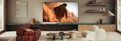 BRAVIA 7 II on its Mirage Stand displaying a dynamic action scene in a modern living room