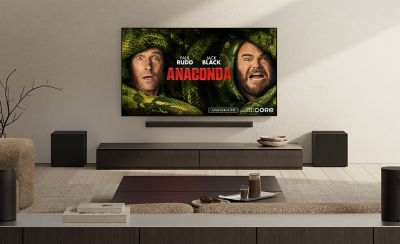Living room with wall-mounted TV displaying the film poster for Anaconda, starring Paul Rudd and Jack Black, as part of the Sony Pictures Core promotion. A soundbar and speakers are arranged beneath the screen.