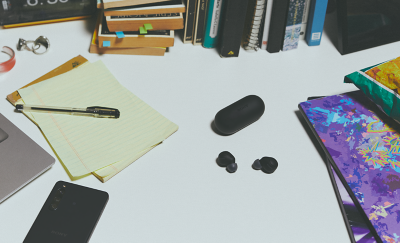 黑色 WF-C700N 耳塞式耳機與充電盒放在雜亂的工作桌上。