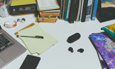 黑色 WF-C700N 耳塞式耳機與充電盒放在雜亂的工作桌上。