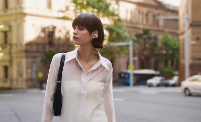 Persona con unos auriculares LinkBuds Clip en lavanda caminando por la calle de una ciudad