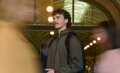 분주한 기차역에서 LinkBuds Clip 이어폰을 착용한 사람