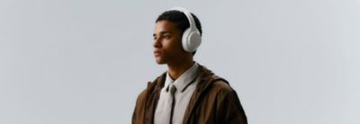 Hombre joven con audífonos plateados WH-1000XM4C de Sony, retrato sofisticado de estilo de vida urbano
