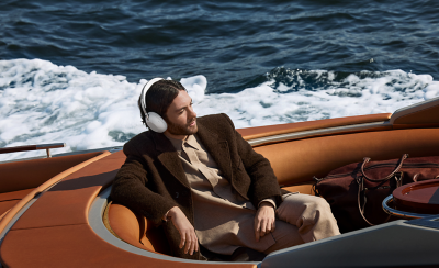 A person wearing a pair of white 1000X THE COLLEXION headphones in a boat on water