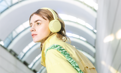 Une personne équipée d'un casque Sony WH-CH520 jaune et portant une veste élégante qui s'harmonise avec le casque.