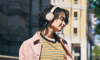 תמונה של גברת הנהנית מהאזנה למוזיקה דרך אוזניות Sony WH-CH520 שלה בצבע בז'