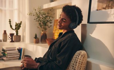 Изображение мужчины в домашней обстановке, который наслаждается прослушиванием музыки через черные наушники Sony WH-CH720