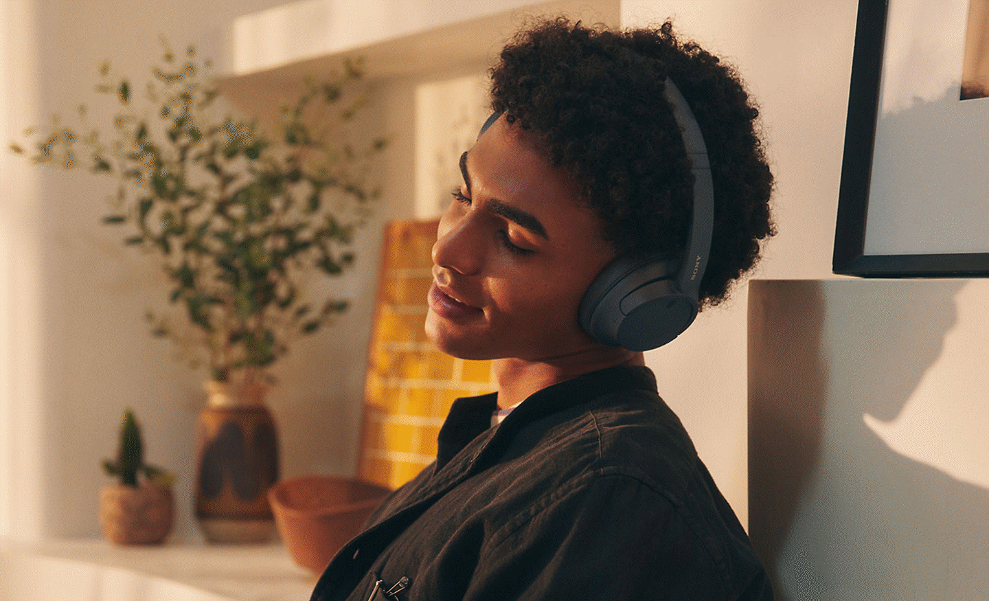 Hình ảnh một người đàn ông đang thưởng thức âm nhạc bằng cặp tai nghe Sony WH-CH720 màu đen tại nhà